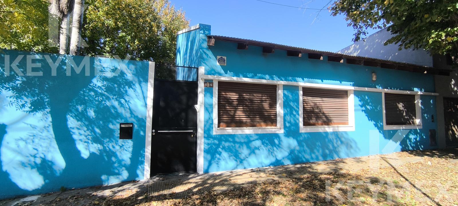 Fachada exterior — portón de acceso y ventanas con persianas de madera