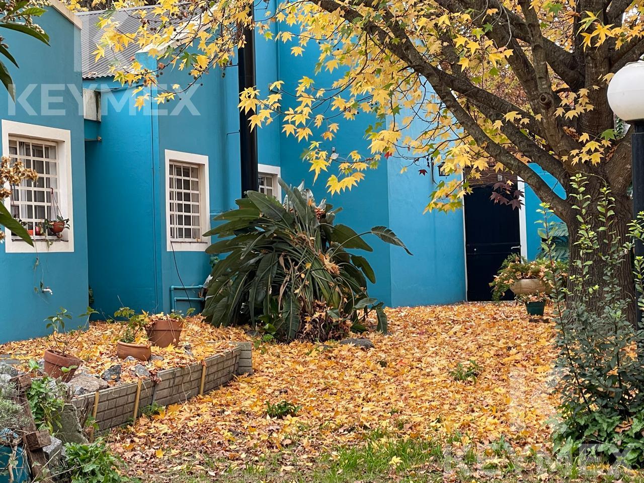 Fachada principal — casa azul con follaje otoñal dorado