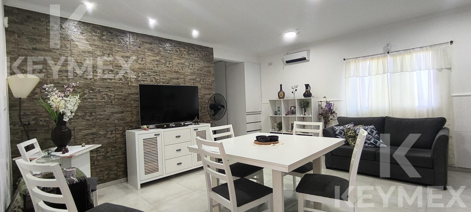 Living con pared de piedra vista y TV